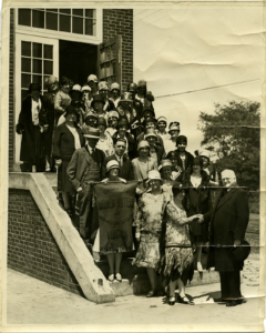 Members of the Organized Women Voters with unnamed men and OWV banner on building exterior steps, 1930